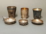 Plusieurs tasses et cuillères en argent sont alignées sur une surface grise
