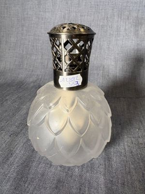 un petit vase en verre avec un couvercle en argent, sur fond gris