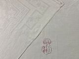 a close up of a white table cloth with a red monogram on it