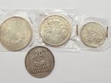 trois pièces d'argent dans des sachets en plastique, posées sur une surface blanche