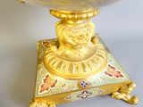 a gold vase sitting on top of a small stand