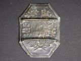 a silver plate with a picture on it on a black surface