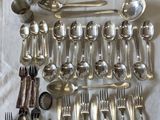 a lot of silverware on a table with a white cloth