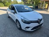 une voiture blanche garée sur un parking, avec des arbres en arrière-plan