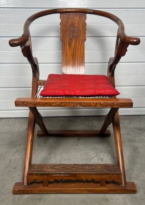 une chaise en bois sur laquelle est posé un coussin rouge