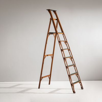 une vieille échelle en bois appuyée contre un mur blanc