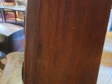 a tall wooden clock sitting on top of a wooden table