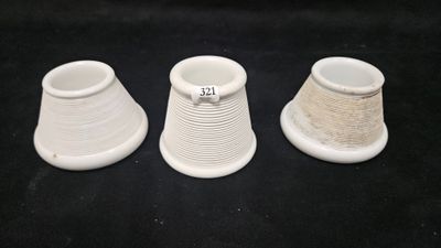 three white vases are lined up on a black surface