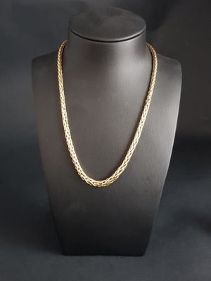 a gold necklace on a mannequin with a black background