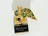 une broche dorée et verte sur laquelle est représenté un oiseau