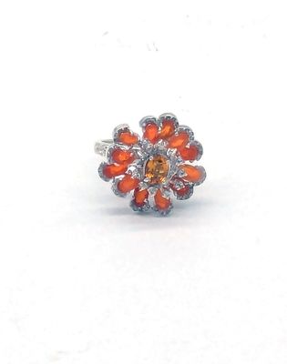 une image représentant une bague sertie de pierres orange sur un fond blanc