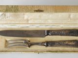deux couteaux et une fourchette dans une boîte posée sur une table