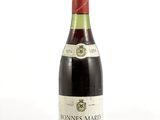 une vieille bouteille de vin posée sur une surface blanche