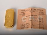 a gold bar next to a piece of paper on a table