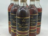 quatre bouteilles de vin sont alignées sur une surface blanche