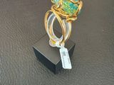 a gold ring with a green stone on top of it