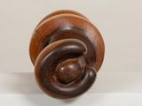 a wooden sculpture of a spiral design on a white surface