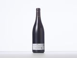 the bottle of wine is sitting on the table on a white surface