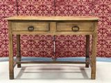 an old wooden table with two drawers and a lamp on top