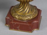 a gold vase with a red base on a gray surface