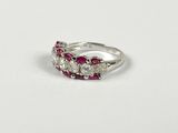 a close up of a diamond and ruby ring on a white surface