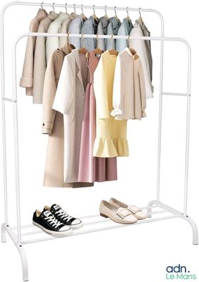 un portant avec des vêtements suspendus et une paire de chaussures à côté