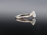 an engagement ring with a pear shaped diamond on a reflective surface