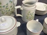 many cups and saucers on a table with a teapot