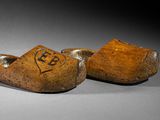 pair of wooden clogs with initials on them on a gray surface