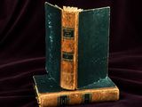two books sitting on top of each other on a purple cloth