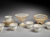 une image représentant un ensemble de plats et de tasses blancs et dorés