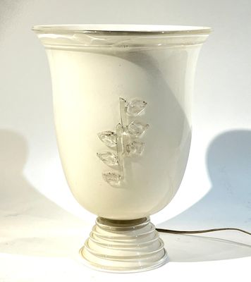 un vase blanc posé sur une table, auquel est attaché un cordon
