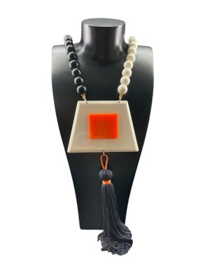 un gros plan d'un collier porté par un mannequin, orné d'un pompon