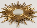 brass sunburst mirror with a mirror in the middle of it