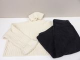 deux paires de pulls noirs et blancs et de jeans posés sur une surface blanche