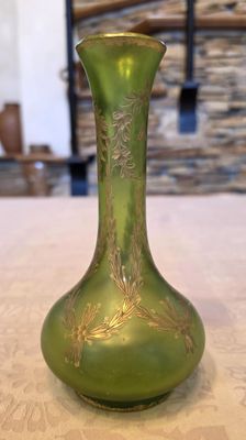 un vase vert posé sur une table, avec un mur de pierre en arrière-plan