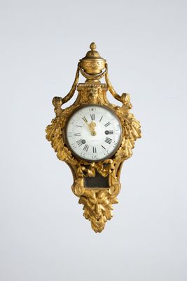a gold clock hanging from the side of a wall