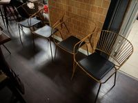 QUATRE FAUTEUILS en métal doré l'assise en simili cuir noir