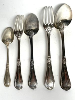 five spoons and a fork are lined up on a white surface