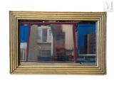 reflet d'un bâtiment dans un miroir posé sur un mur blanc