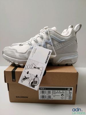 un gros plan sur une paire de baskets blanches posées sur une boîte