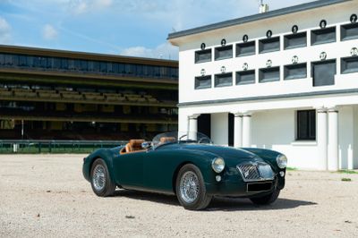 a green sports car parked in front of a white building