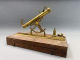 un télescope ancien en laiton posé sur un socle en bois, sur fond blanc