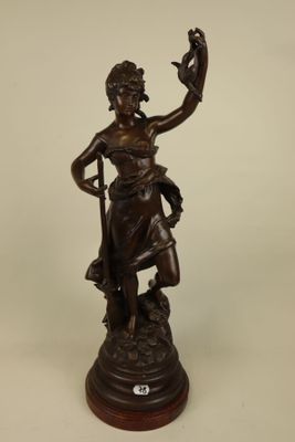 an antique bronze statue of a woman with a bird on her arm
