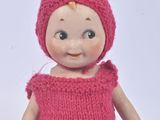 a small doll that is wearing a pink knitted outfit