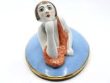 a figurine of a woman sitting on a blue plate