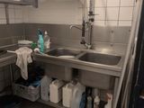 a kitchen with a sink and a lot of cleaning supplies on the counter