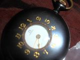 une montre de poche noire avec des chiffres dorés