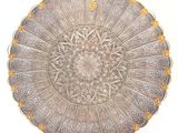 silver plate with gold decoration on it on a white surface