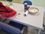 a white table with blue chairs and a red jacket on it
